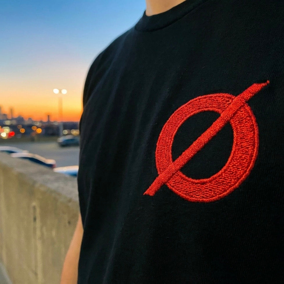 Close-up of the red embroidered Ø chest detail on the DAY ONE Ø Tee black shirt #group:black-red