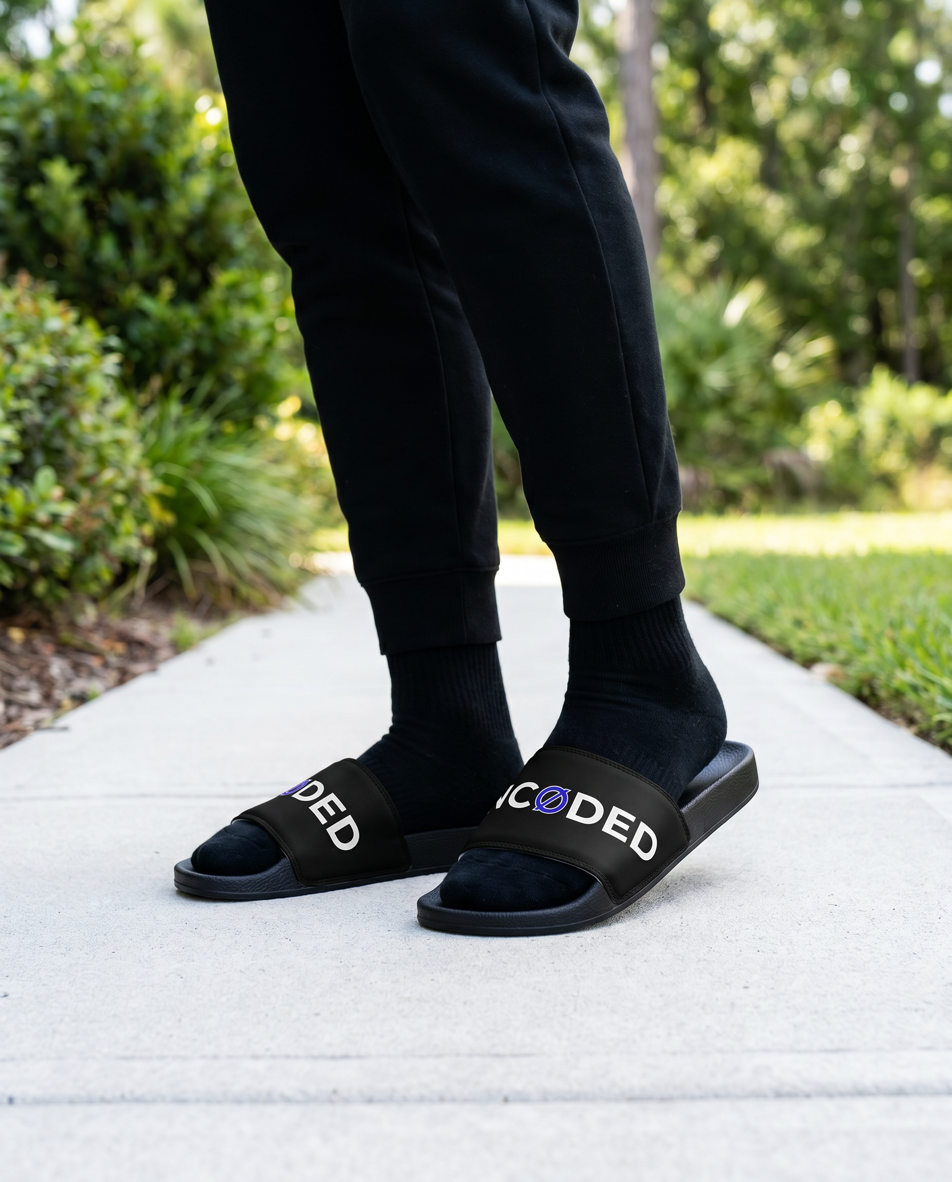 Person standing in UNCØDED Logo Slides black strap streetwear sandals #group:black-blue