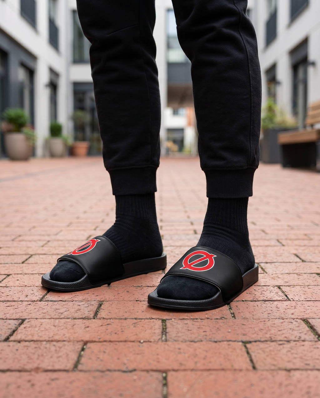 Person standing in UNCØDED Ø Slides with red Ø logo streetwear sandals #group:black-red