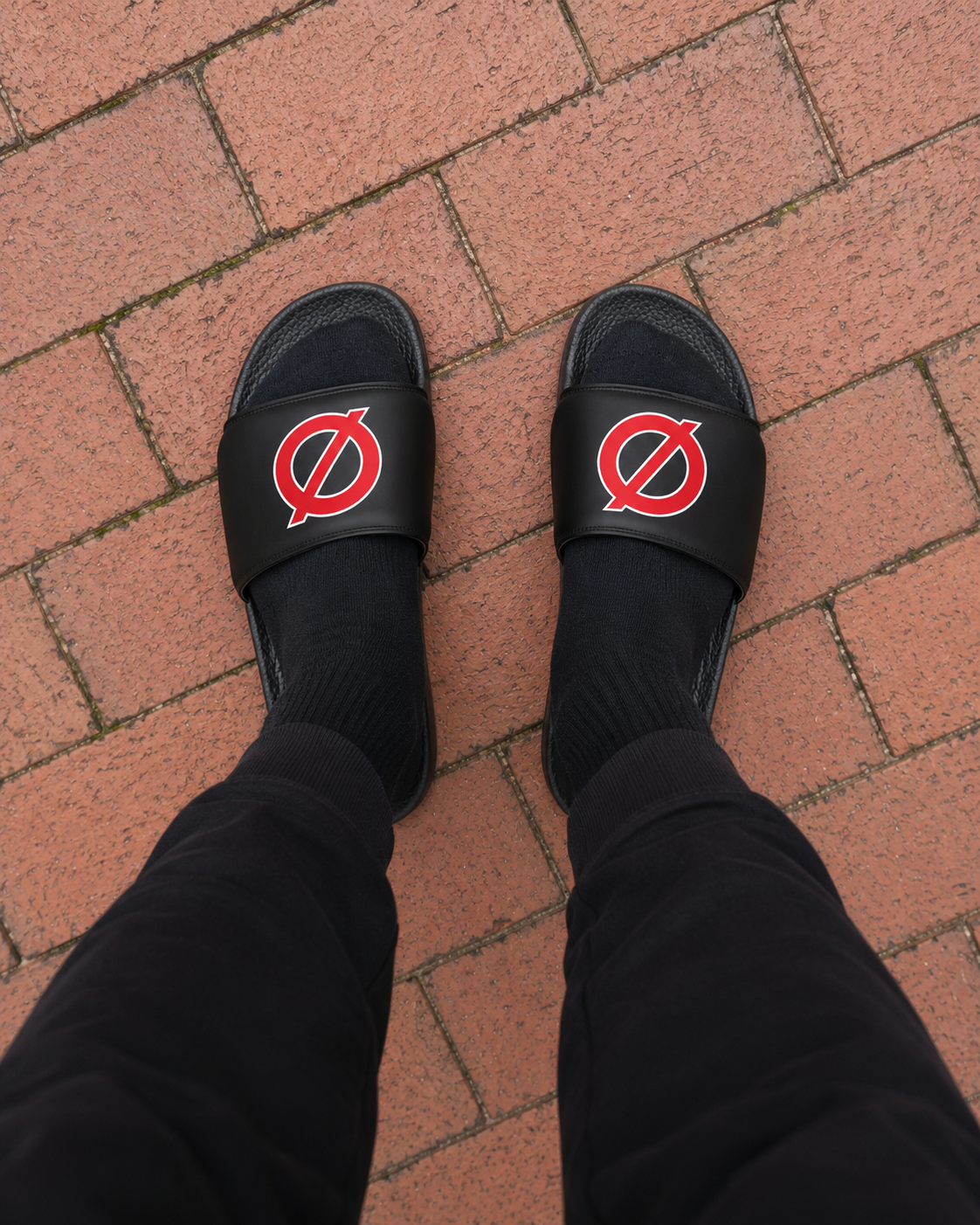 Person wearing UNCØDED Ø Slides with red Ø logo top-down view #group:black-red